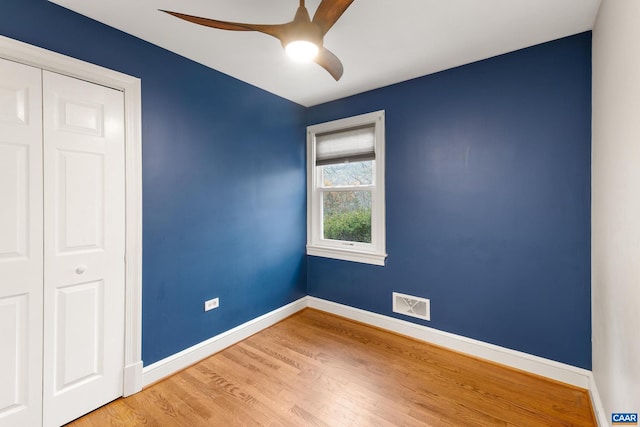 unfurnished bedroom with ceiling fan, wood finished floors, visible vents, baseboards, and a closet