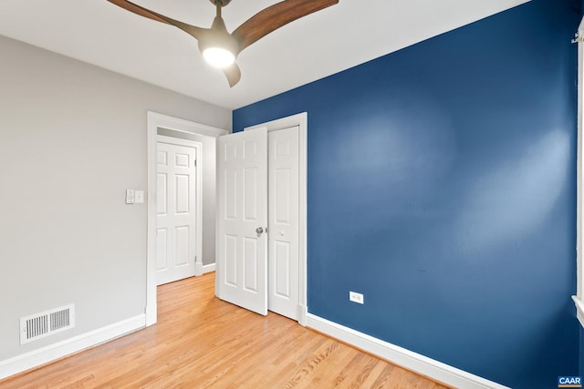 empty room featuring light wood finished floors, baseboards, visible vents, and a ceiling fan