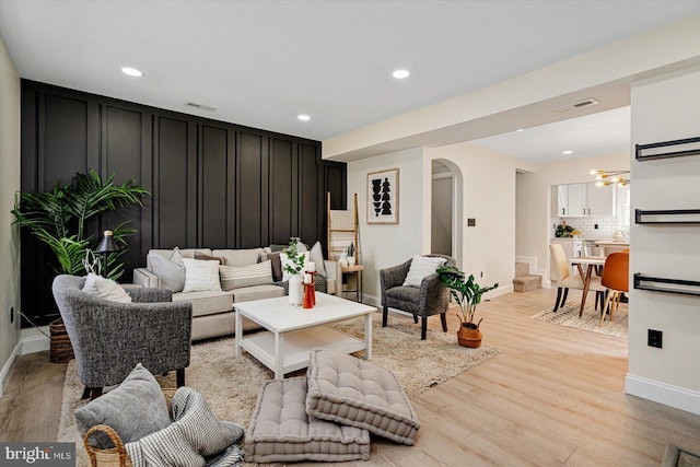 living room featuring arched walkways, recessed lighting, visible vents, and light wood-style floors