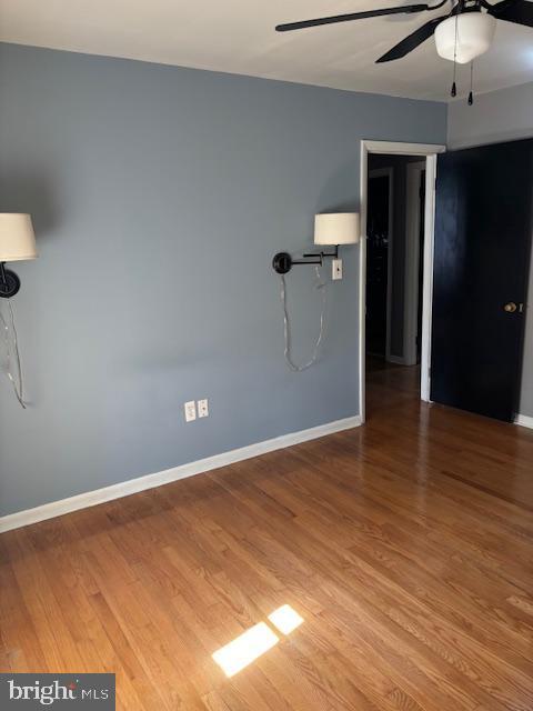 empty room featuring ceiling fan, wood finished floors, and baseboards