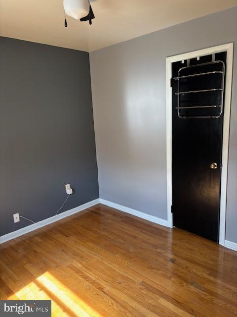 unfurnished room with ceiling fan, baseboards, and wood finished floors