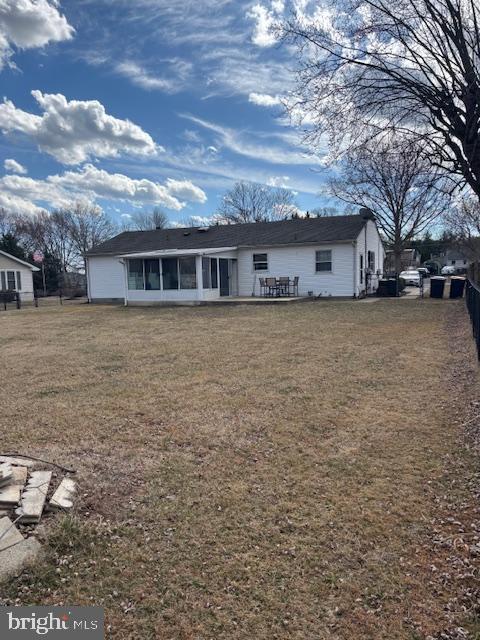 view of front of house with a front lawn, fence, and a sunroom