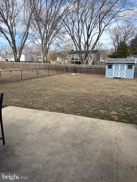 view of yard with an outbuilding, a fenced backyard, a patio, and a shed