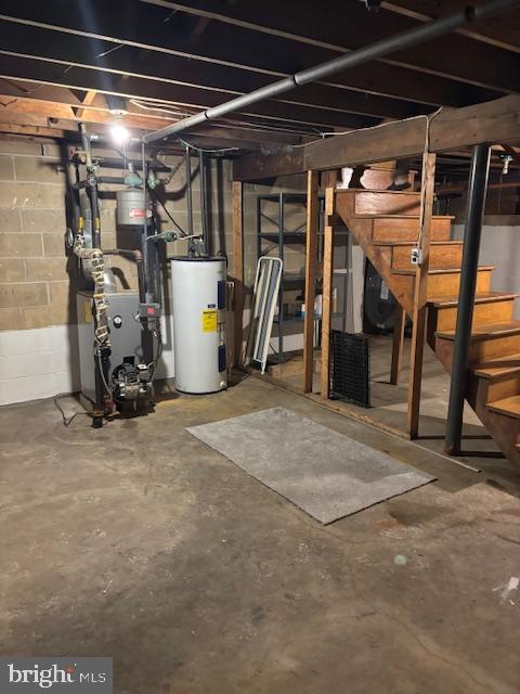 unfinished basement with a heating unit, electric water heater, concrete block wall, and stairs