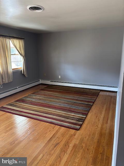 empty room with wood finished floors and visible vents