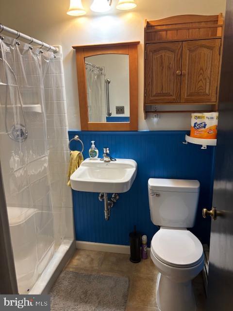 bathroom featuring toilet, a shower stall, a sink, and tile patterned floors