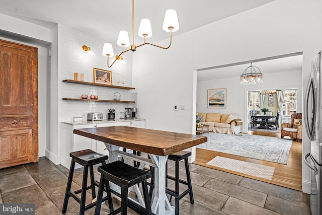 dining space featuring a toaster, stone finish flooring, and a chandelier