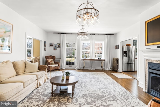 living room with wood finished floors, a fireplace, and an inviting chandelier