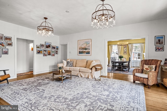 living room with baseboards, a chandelier, and wood finished floors