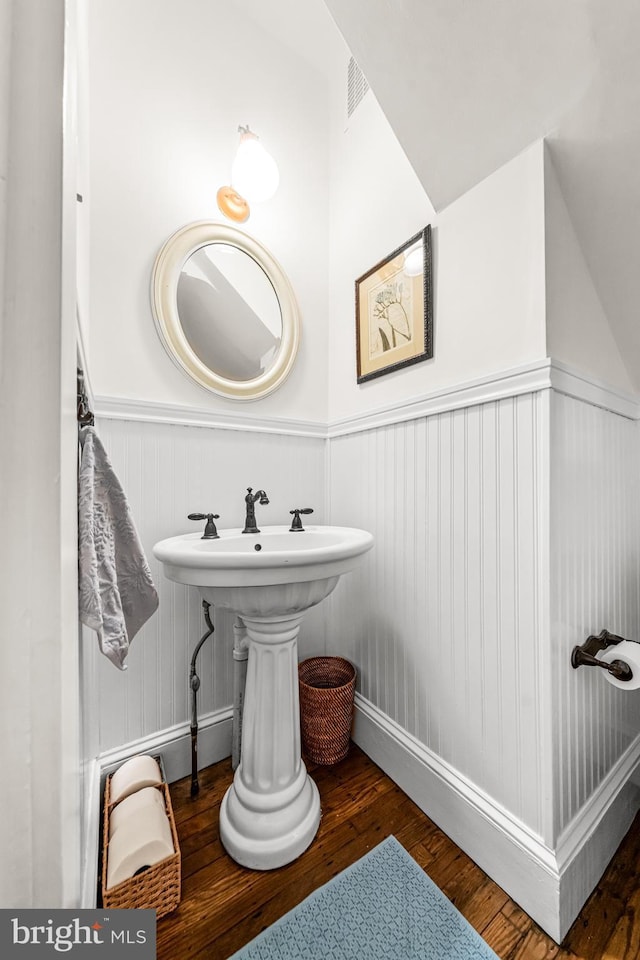 bathroom with a wainscoted wall, visible vents, and wood finished floors