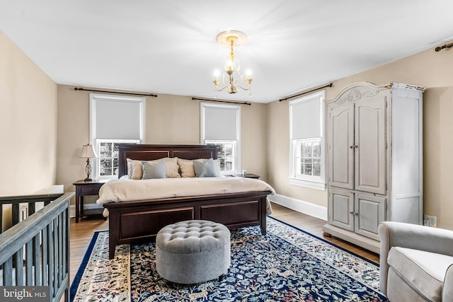 bedroom with light wood-type flooring, baseboards, and an inviting chandelier