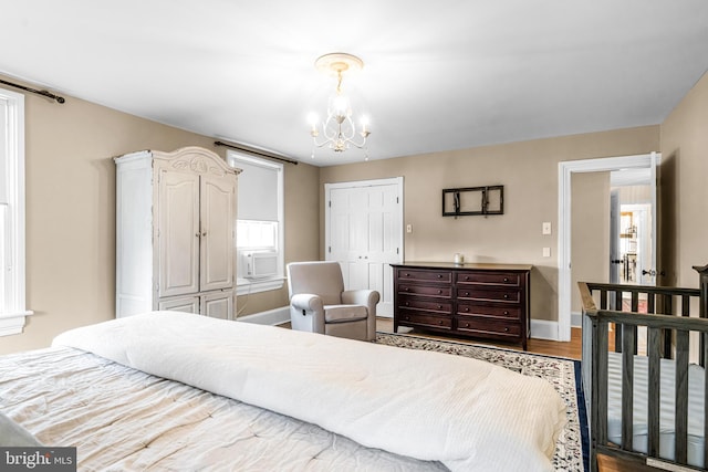 bedroom featuring a closet, an inviting chandelier, wood finished floors, and baseboards