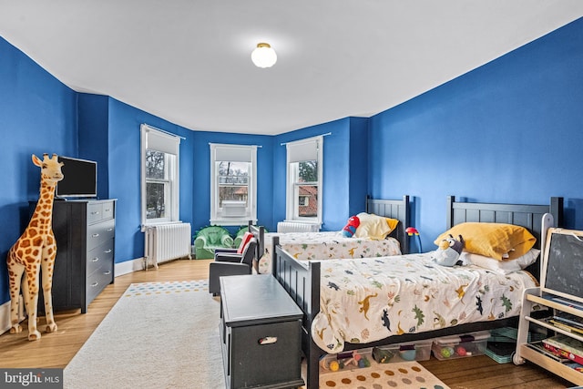 bedroom with radiator heating unit and wood finished floors