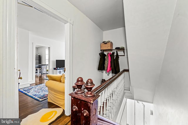 corridor featuring wood finished floors and an upstairs landing