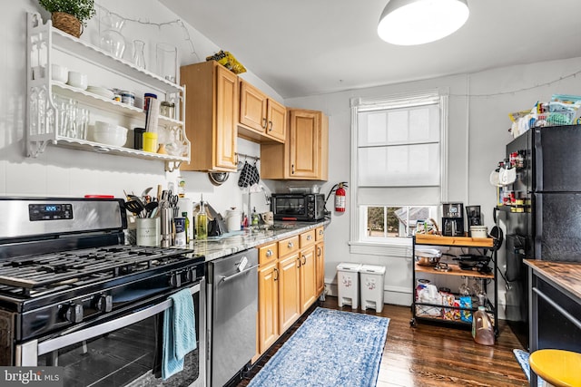 kitchen with freestanding refrigerator, dark wood-style flooring, light stone countertops, and gas range