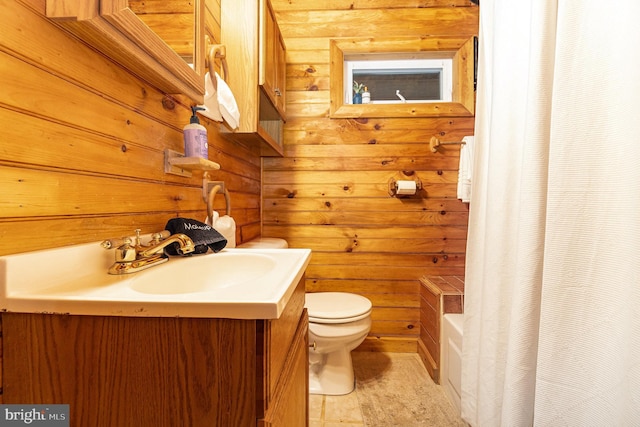 bathroom featuring toilet, wood walls, and vanity