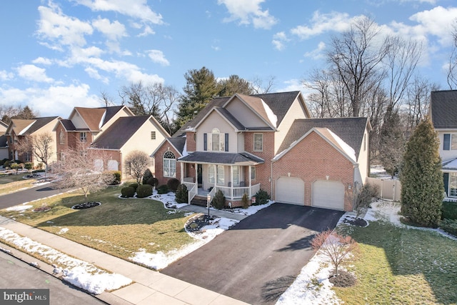 traditional home featuring aphalt driveway, a porch, a front yard, an attached garage, and brick siding