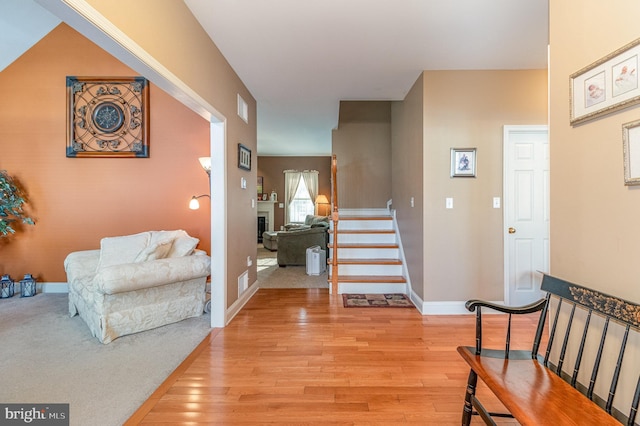 entrance foyer with stairway, visible vents, baseboards, a fireplace, and light wood-style floors