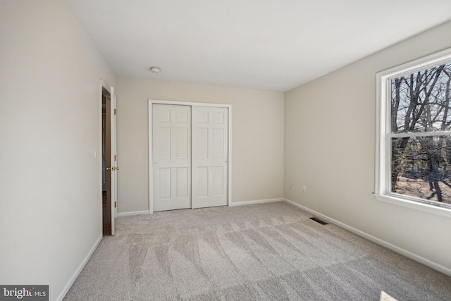 unfurnished bedroom with a closet, baseboards, visible vents, and carpet floors