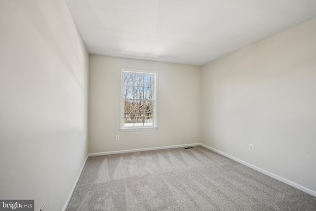 carpeted spare room with visible vents and baseboards