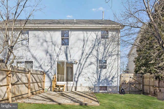 back of property with a gate, entry steps, a patio, fence, and a yard