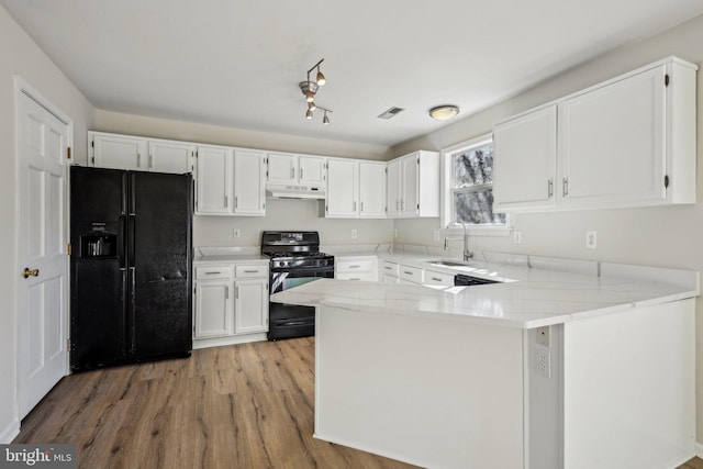 kitchen with black appliances, light wood-style flooring, a sink, a peninsula, and white cabinets