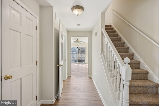 stairway with visible vents, wood finished floors, and baseboards