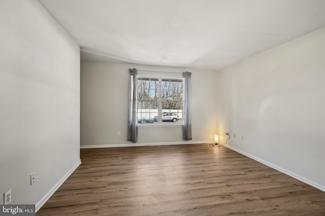 spare room with baseboards and wood finished floors