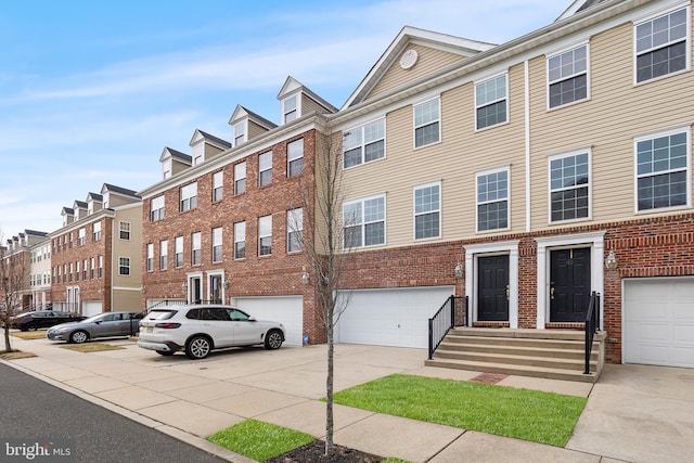 townhome / multi-family property featuring driveway, brick siding, and an attached garage