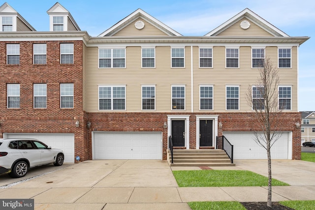 view of property with a garage, brick siding, and driveway