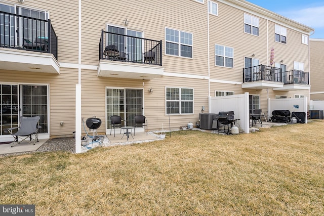 back of property featuring a balcony, a patio area, cooling unit, and a yard