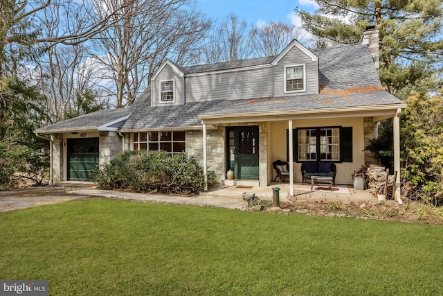 view of front of home featuring a porch, a garage, a shingled roof, stone siding, and a front lawn