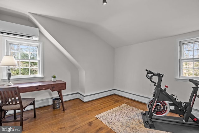 exercise area featuring lofted ceiling, a wall mounted air conditioner, and wood finished floors