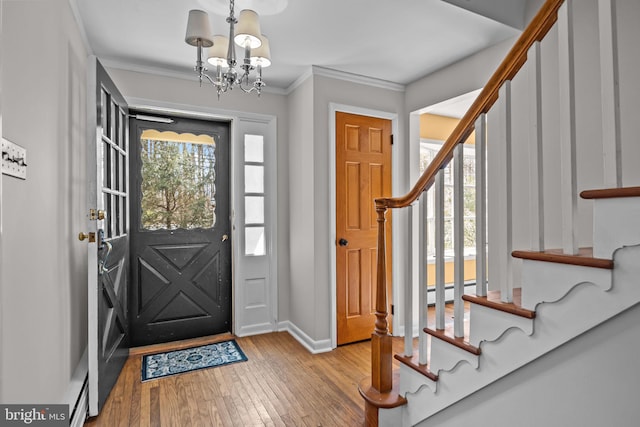 entryway featuring a wealth of natural light, stairway, crown molding, and wood finished floors