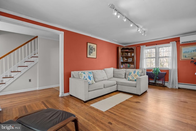 living area featuring wood finished floors, baseboards, stairs, a wall mounted air conditioner, and rail lighting