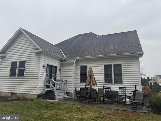 rear view of property with a patio, a yard, and roof with shingles