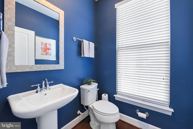 half bath featuring baseboards, a sink, and toilet