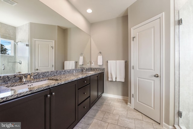 bathroom with a stall shower, a sink, baseboards, and double vanity