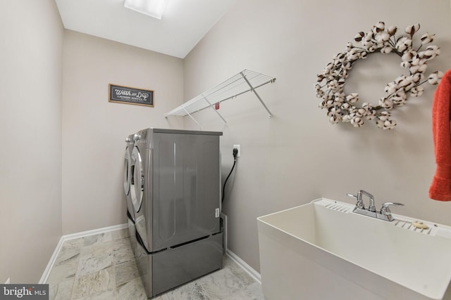 washroom with laundry area, baseboards, marble finish floor, washing machine and dryer, and a sink