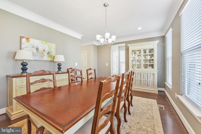 dining space featuring crown molding, dark wood-type flooring, visible vents, baseboards, and an inviting chandelier