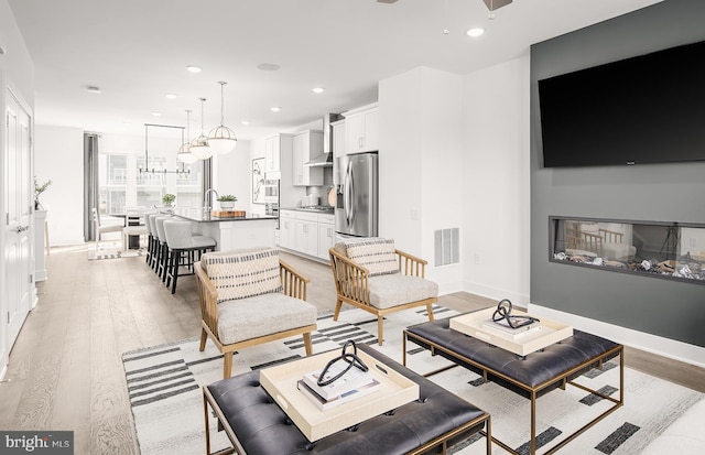 living room with light wood finished floors, baseboards, visible vents, and recessed lighting