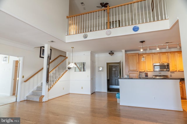 kitchen with dark countertops, stainless steel microwave, light wood-style flooring, and crown molding