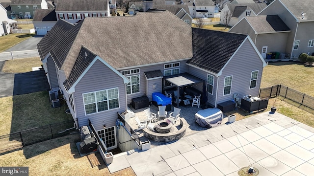 rear view of property featuring a fire pit, a shingled roof, central AC, a fenced backyard, and a patio area