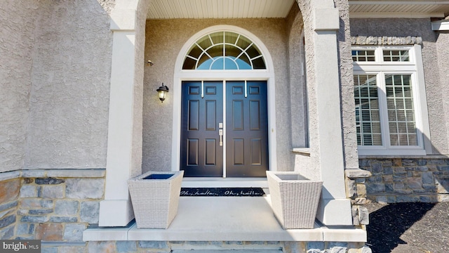 entrance to property with stone siding and stucco siding