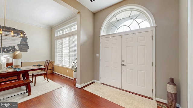 foyer entrance with baseboards, wood finished floors, and ornamental molding