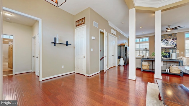 entryway featuring visible vents, baseboards, ornamental molding, decorative columns, and wood finished floors