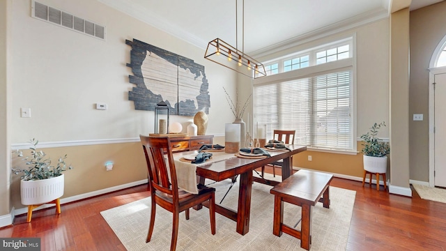 dining area featuring hardwood / wood-style flooring, baseboards, visible vents, and ornamental molding