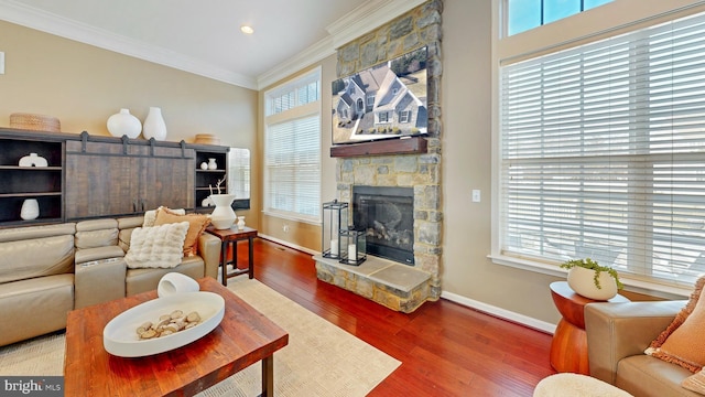 living room featuring a fireplace, wood finished floors, baseboards, and ornamental molding