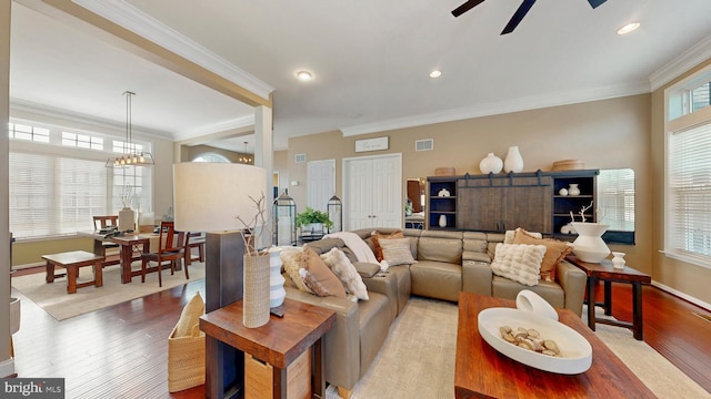 living room with visible vents, crown molding, recessed lighting, ceiling fan with notable chandelier, and wood finished floors