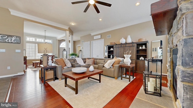 living room with visible vents, a ceiling fan, wood finished floors, crown molding, and baseboards